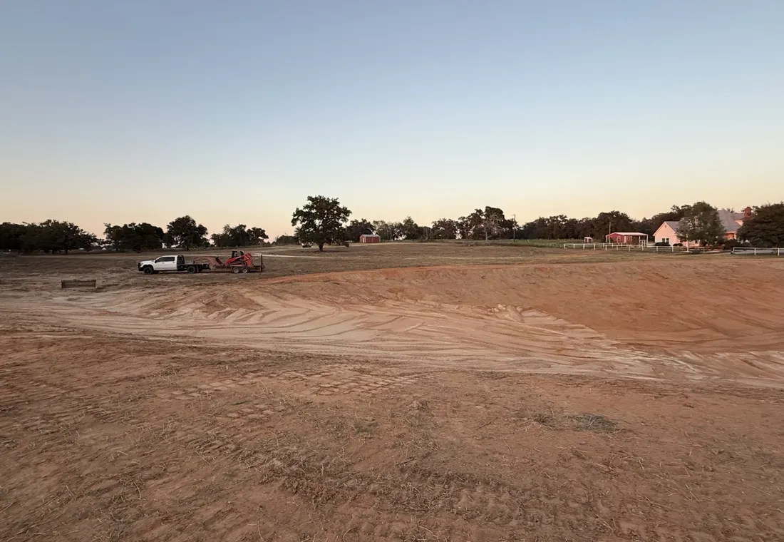 A finished stock tank at dusk with graded, cleared banks